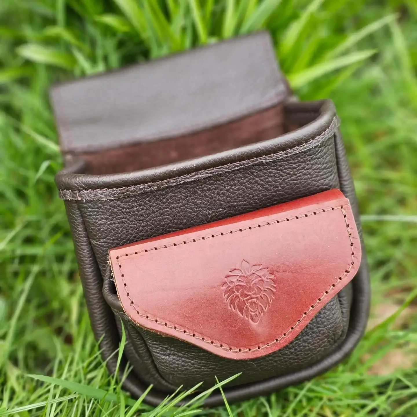 Brown leather cartridge bag with red pocket.