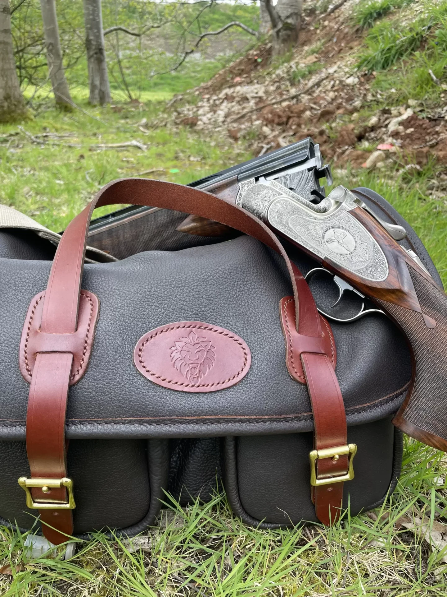 Black sporting bag with brown straps in the field.