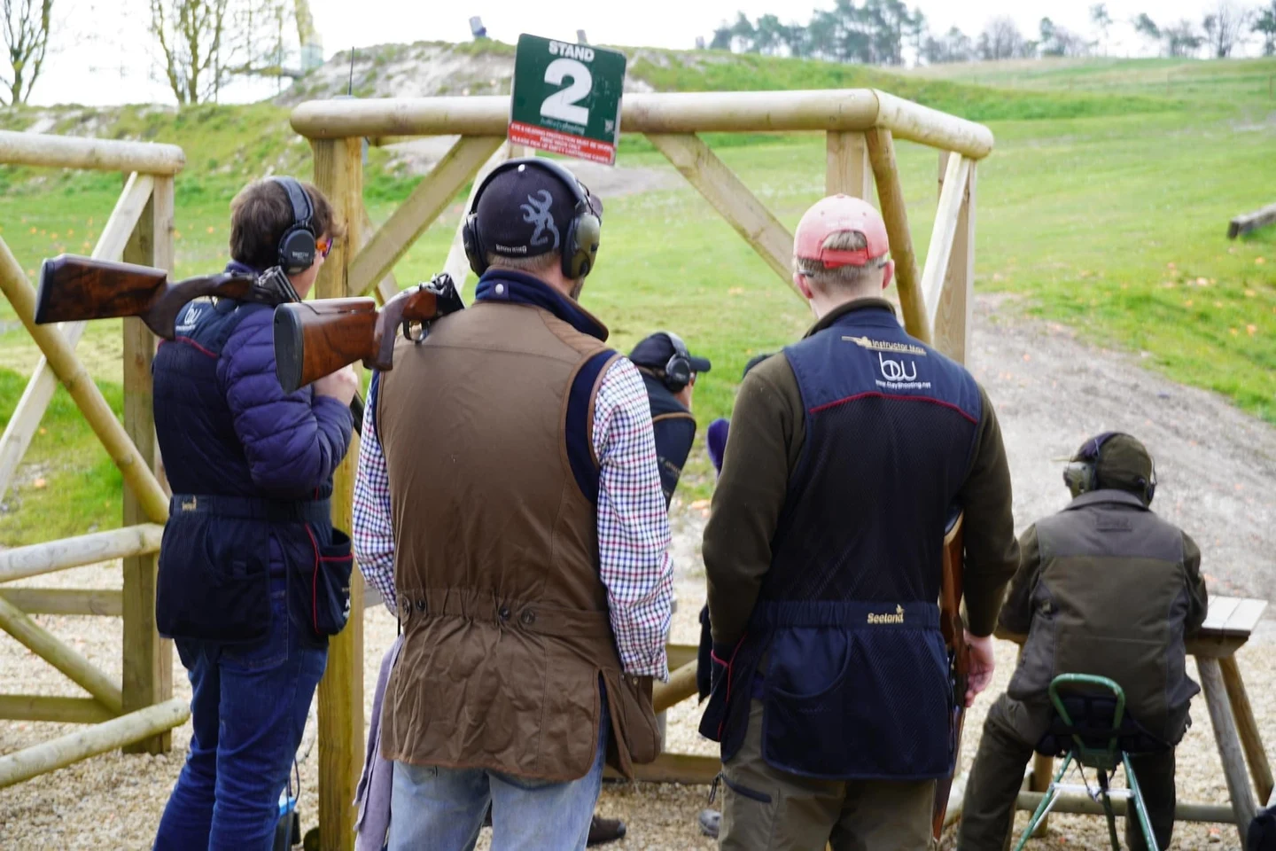 A group of shooters waiting together at a numbered clay stand.