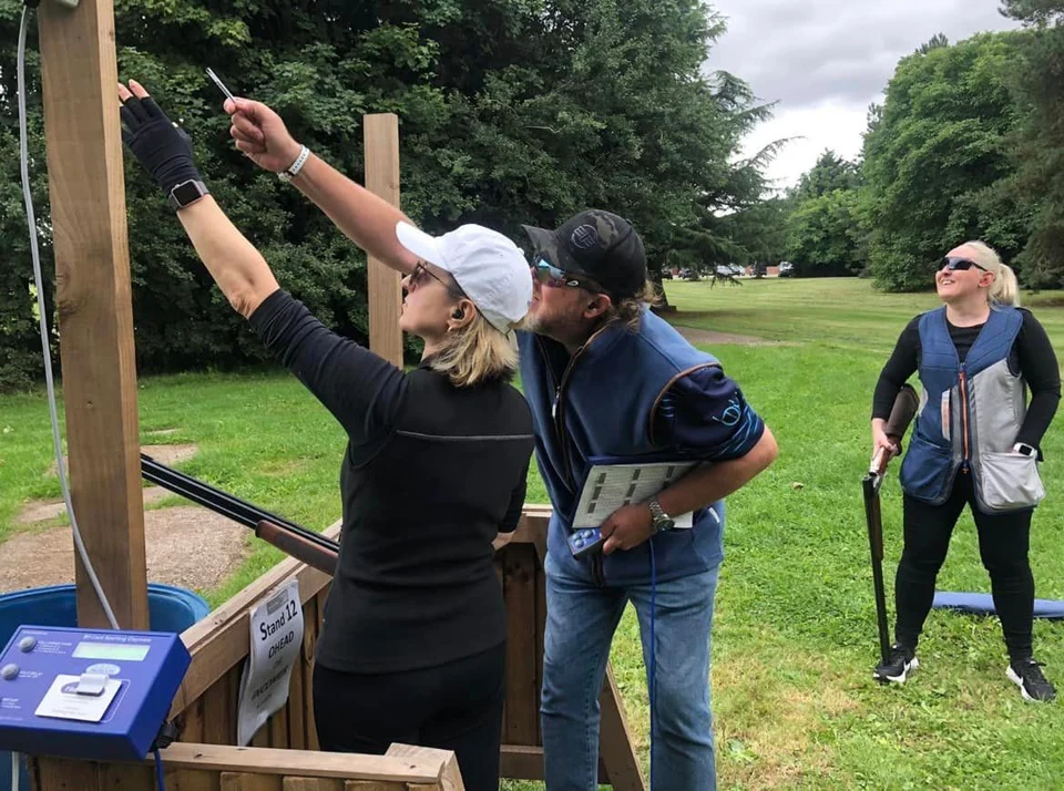 An instructor helping a woman identify the flight of a clay target.